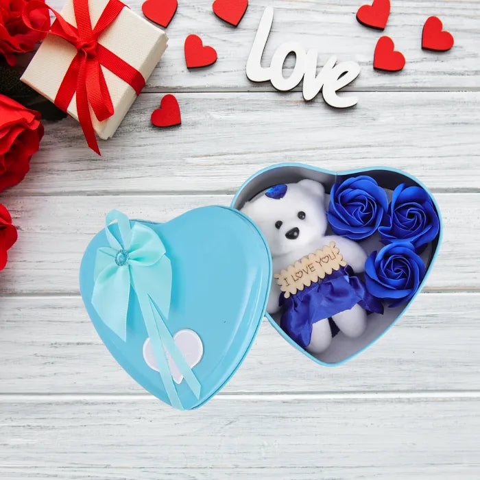 Blue heart-shaped gift box with teddy bear and roses on white wooden background with love decoration