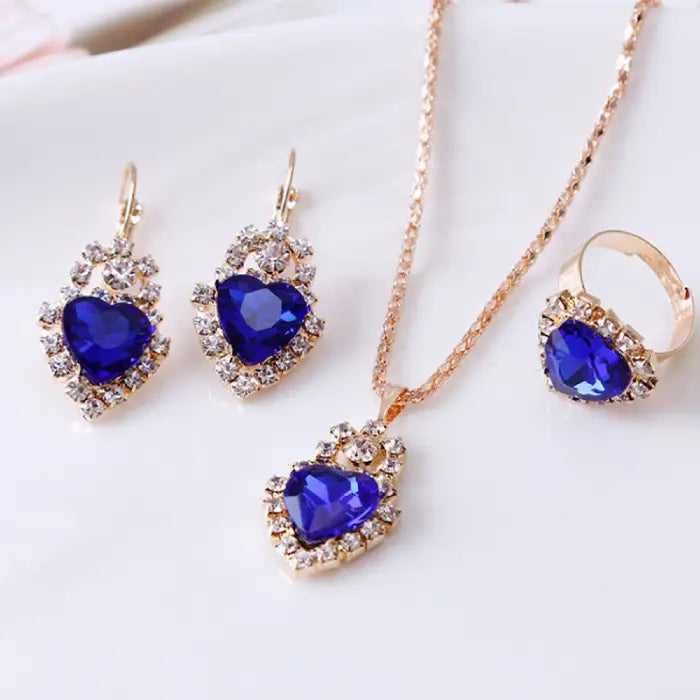 Blue gemstone heart jewelry set with a necklace, earrings, and ring, accented by brilliant crystals.