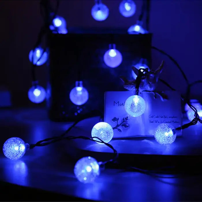 Vibrant blue LED globe lights illuminating dark room, decorative setting with bird figurine and note card