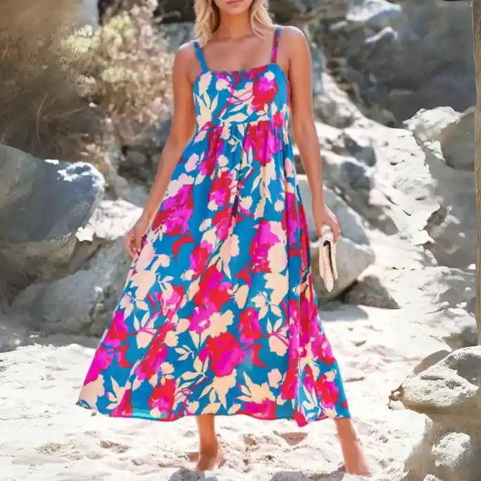 Blue pink floral maxi dress with smocked bodice and adjustable straps on sandy beach
