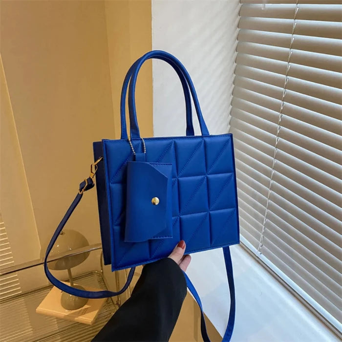 woman holding blue quilted handbag with geometric pattern and gold hardware with strap