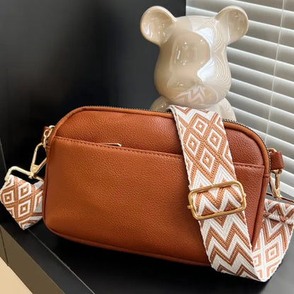 Brown crossbody bag with orange chevron strap, a sophisticated option for everyday use.