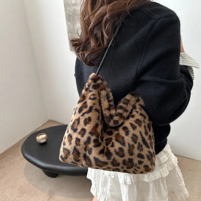 Woman wearing a brown leopard print faux fur handbag with black strap, styled for a casual outfit.