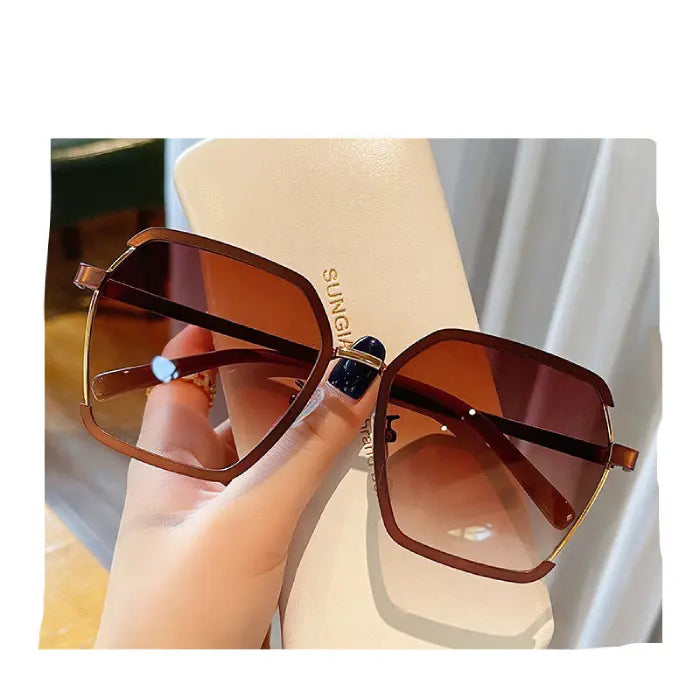 Elegant brown metallic oversized square sunglasses with gradient lenses displayed on luxury cream leather case