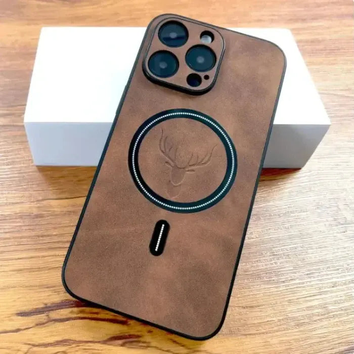 Brown suede iPhone case with deer crest and MagSafe ring on a wooden surface.