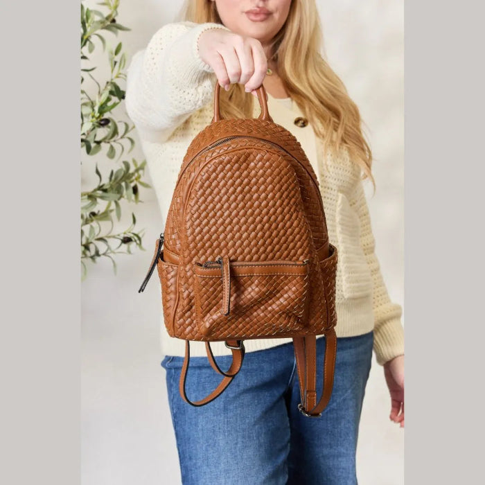 Brown woven leather backpack held by its strap, showcasing elegant design and modern style.