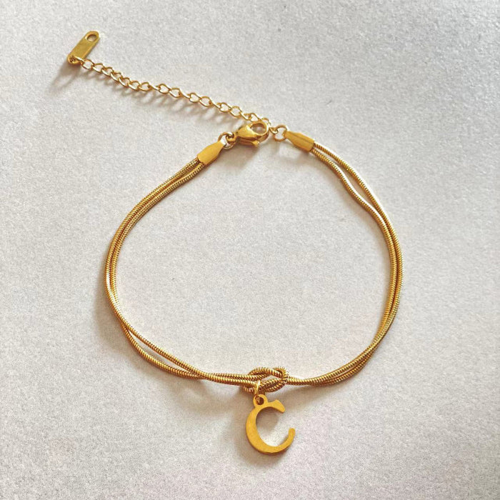 Gold bracelet with a crescent moon charm on a light gray background
