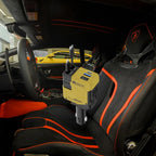 Car charger inside Lamborghini with black and orange interior and yellow sports car visible outside window.