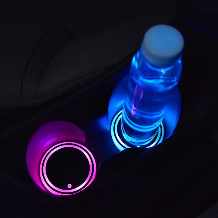 Custom coasters with LED illumination shown in car cup holders with pink and blue glow