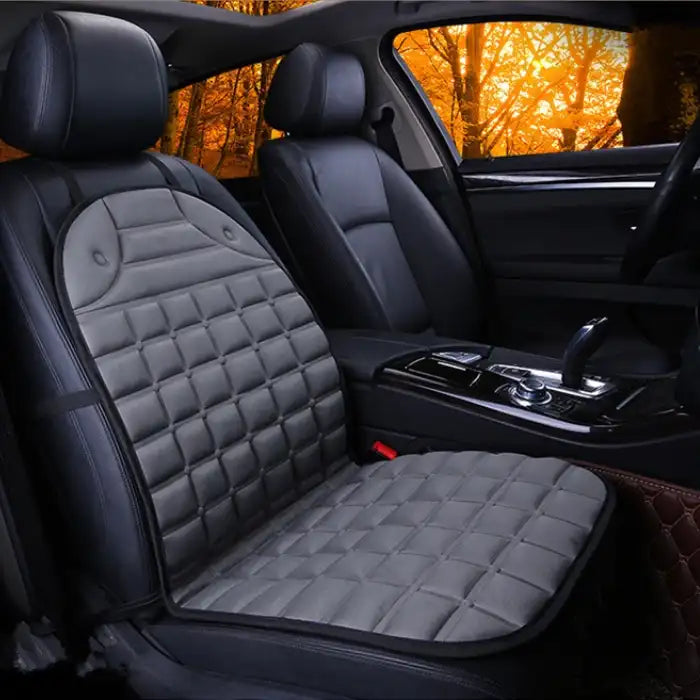 Car Seat Heater grey quilted cushion on single front seat in dark interior with warm lighting.