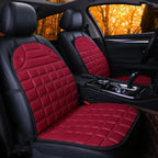 Car Seat Heater red quilted pads on both front seats in dark interior with orange forest view.