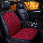 Car Seat Heater red quilted cushion on single front seat in dark interior with warm lighting.