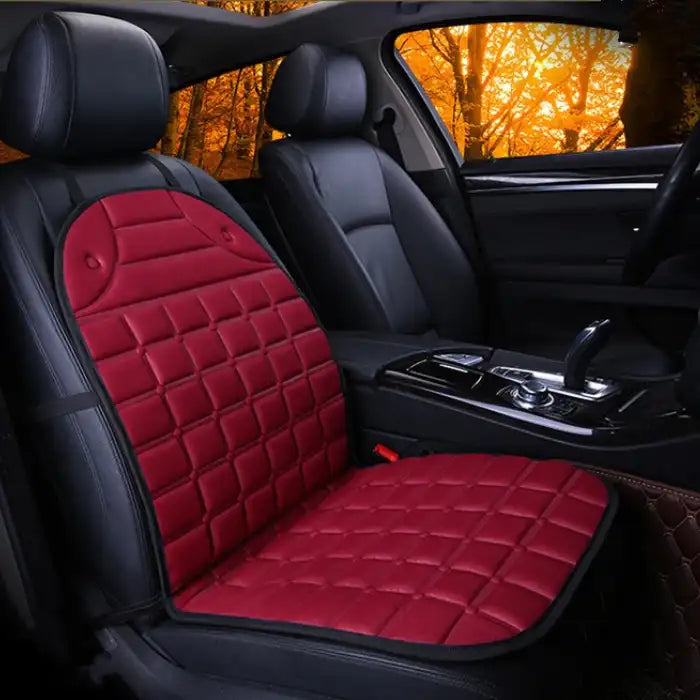 Car Seat Heater red quilted cushion on single front seat in dark interior with warm lighting.
