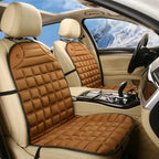 Car Seat Heater tan quilted pads on front car seats with snowy mountain view outside.