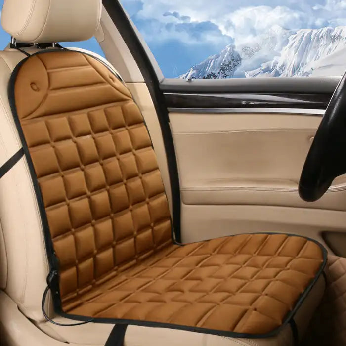 Car Seat Heater tan quilted cushion on beige front car seat with winter scenery outside.