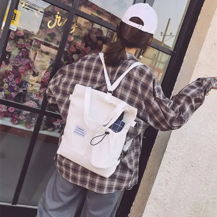 White canvas tote bag with utility pockets styled with plaid shirt and casual wear