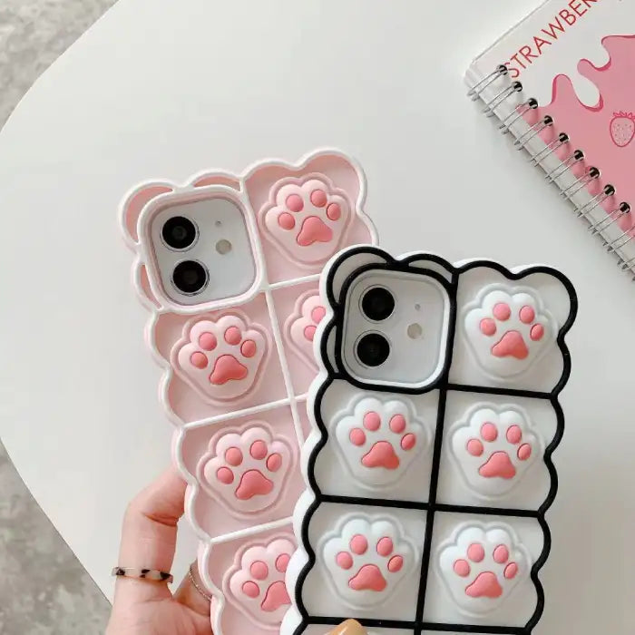 Cat paw phone case in pink and white versions displayed side by side showing 3D silicone texture and cute iPhone case design
