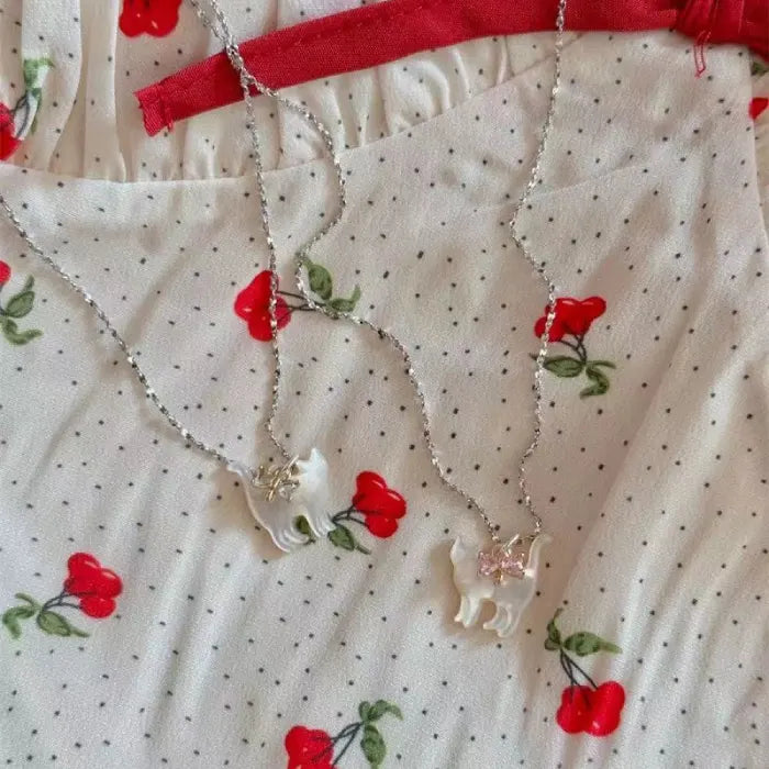 Cat Pendant Necklace pair with mother-of-pearl cat charms placed on cherry-pattern fabric