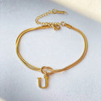 Gold bracelet with a 'U' charm on a light gray background