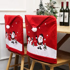 Red Christmas chair covers with Santa and snowman on chairs beside table with wine bottles and mini trees.