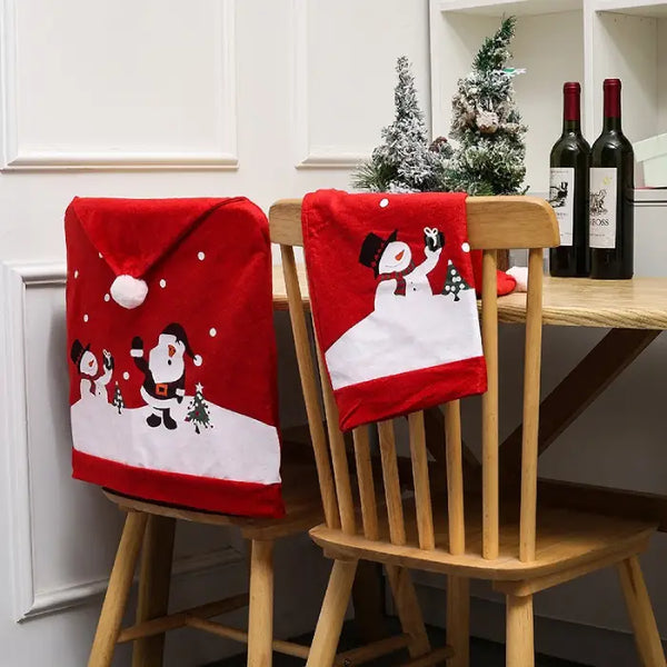 Red Christmas chair covers with snowman and Santa, one folded on chair next to festive tabletop decor.
