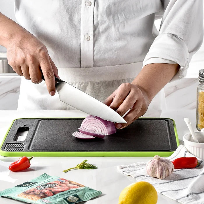 Chef in white slicing red onions on modern cutting board, kitchen essentials.