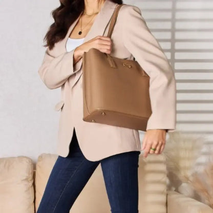 Woman in beige blazer and jeans carrying a tan leather tote bag, emphasizing the bag's versatility with casual outfits