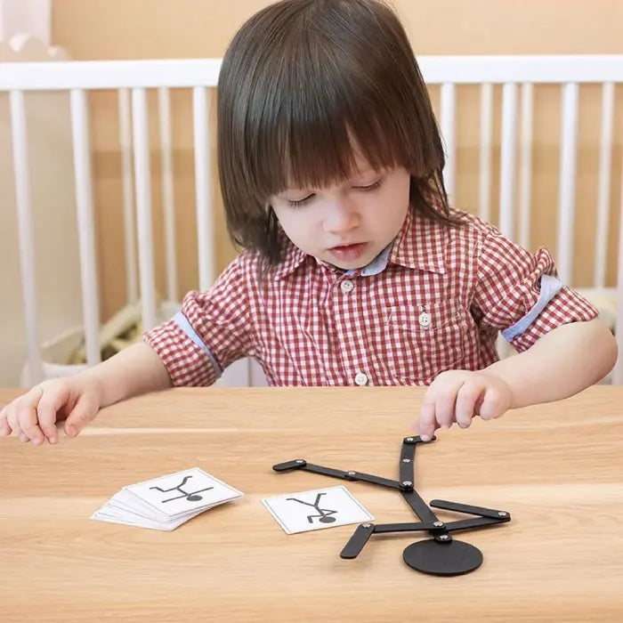 A young child arranging a wooden stick figure with pose cards on a table.