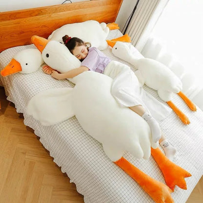 Girl sleeping on large white duck plush toys in a cozy room.