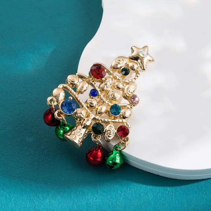 Christmas brooch shaped like a gold Christmas tree with multicolor gems and hanging jingle bells