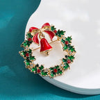 Christmas brooch featuring red bell and holly wreath resting on white decorative surface
