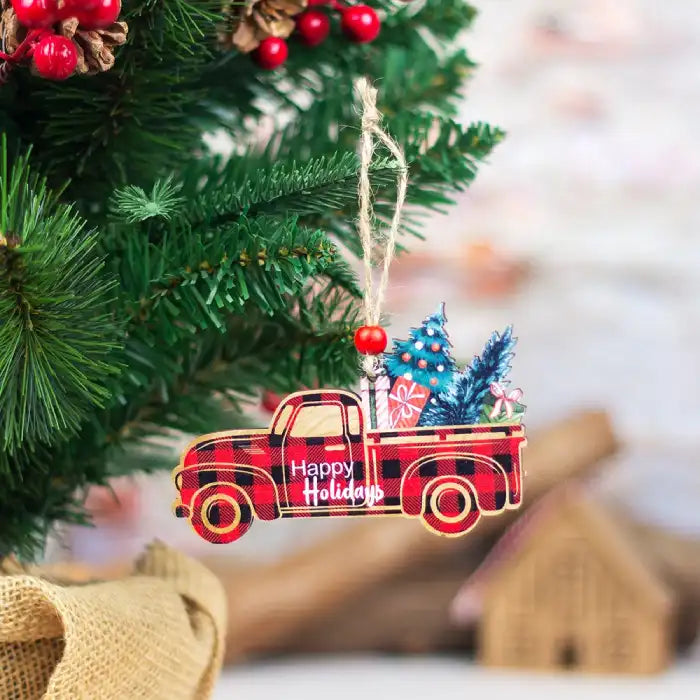 Christmas Decorations red plaid truck ornament hanging on a Christmas tree with gifts and a small tree in the truck bed.