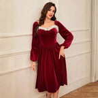 Christmas red velvet dress with sweetheart neckline and long sleeves in a simple indoor setting.