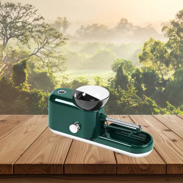 Cigarette Rolling Machine in dark green shown at an angle with natural forest background.