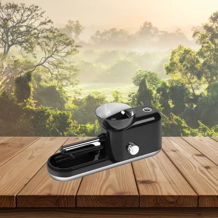 Cigarette Rolling Machine in black color placed on wooden surface with scenic forest view behind.
