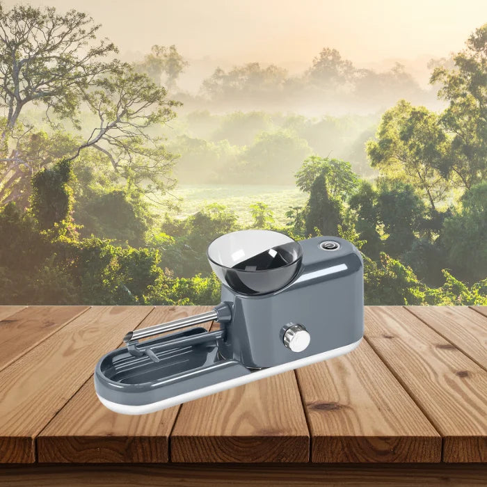 Cigarette Rolling Machine in grey placed on wooden surface with forest view in the background.