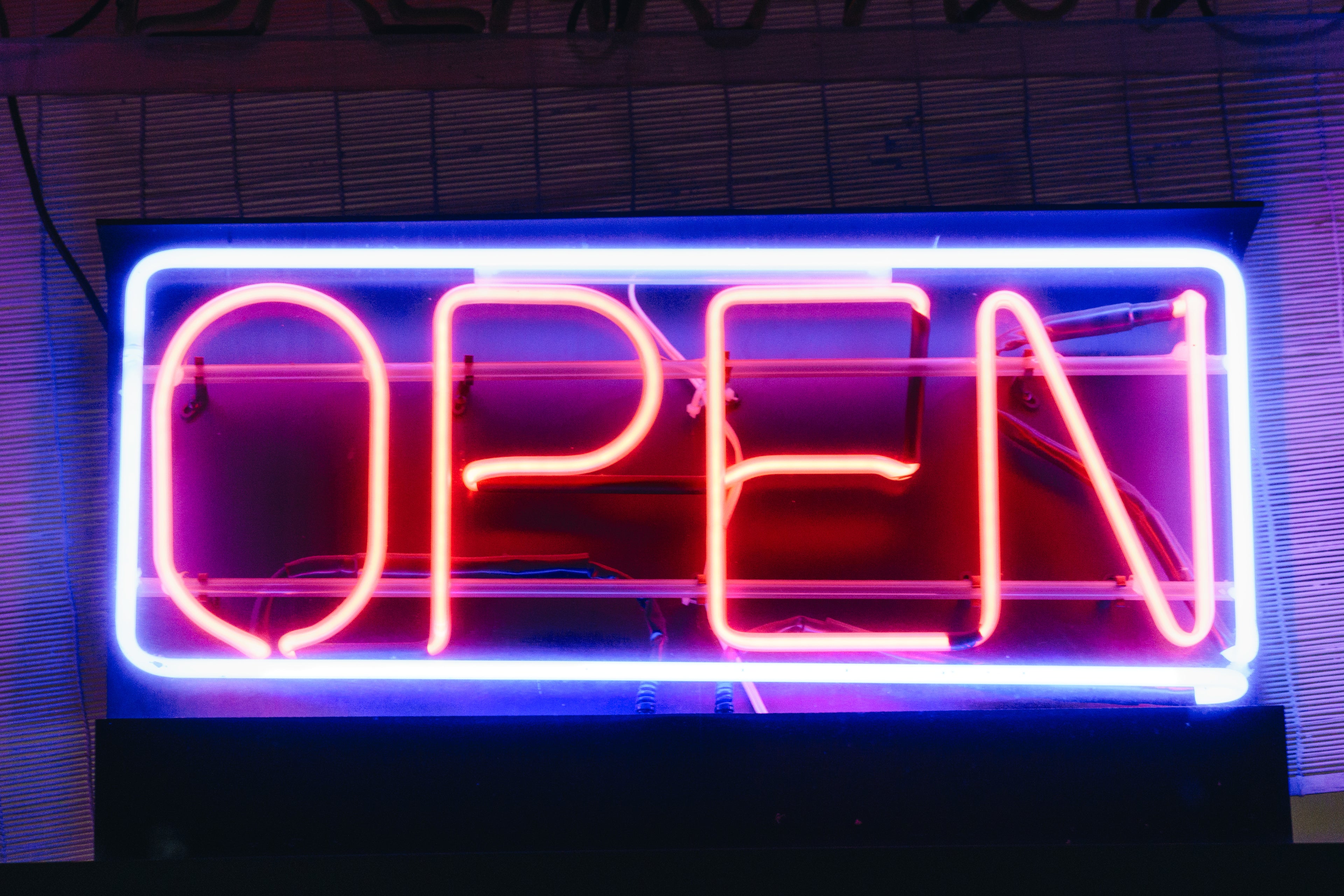 open neon sign.  pink/orange letters with blue/white box around them