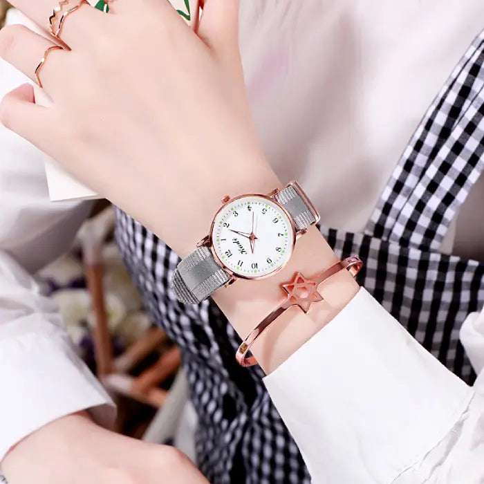 Women's watch with a white dial and gray strap, styled with a rose gold star bracelet.