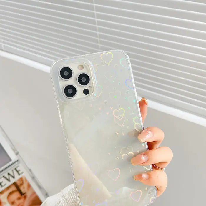 Hand holding a clear phone case with holographic heart accents, perfect for stylish phone protection.