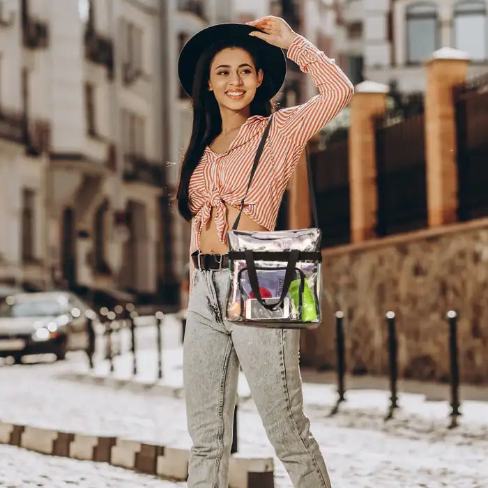 Clear stadium tote bag styled as a shoulder bag in city fashion scene with urban backdrop.