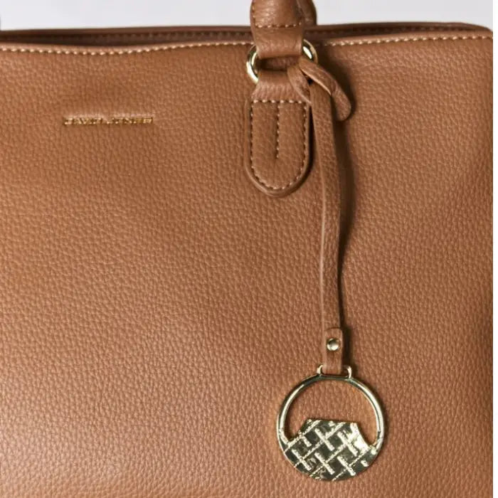  Close-up of brown handbag with distinctive gold charm, ideal for elegance.