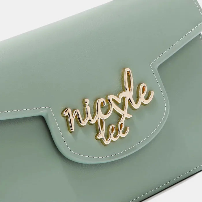 Close-up of gold cursive logo on mint green leather flap of handbag