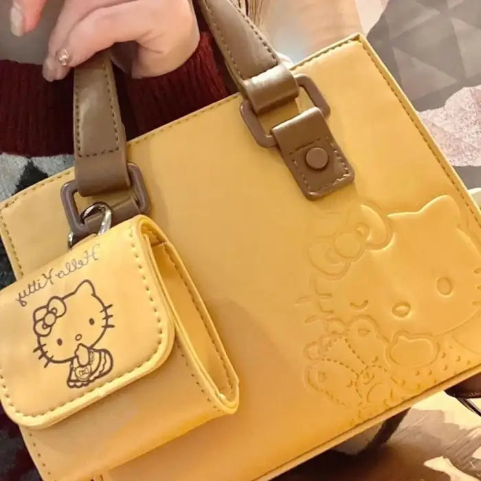 Close-up of yellow Hello Kitty handbag with embossed design and detachable pouch for stylish daily wear.