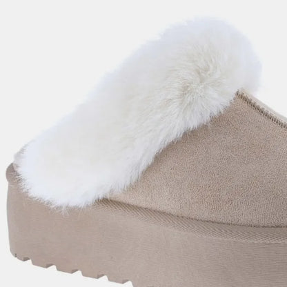 Detailed view of beige suede platform slipper showing textured sole and plush white fur trim construction