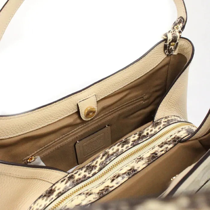 Interior view of Coach tote bag with zip pocket and magnetic closure, featuring snake print accents.