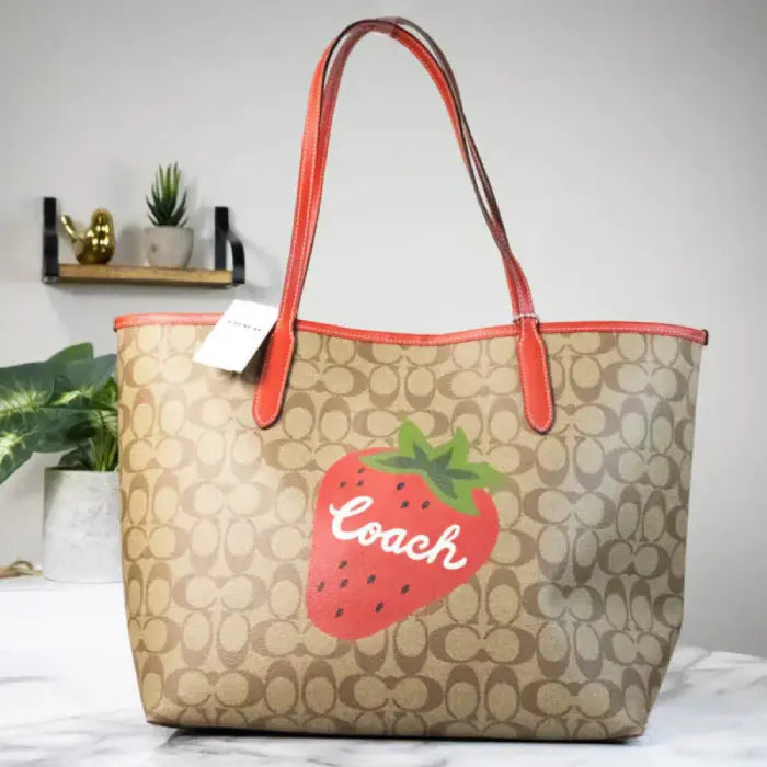 Coach tote bag with strawberry design on display, emphasizing its stylish monogram print.