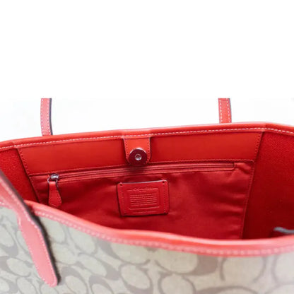 Interior of Coach tote bag with red lining, zip pocket, and branded tag detail.