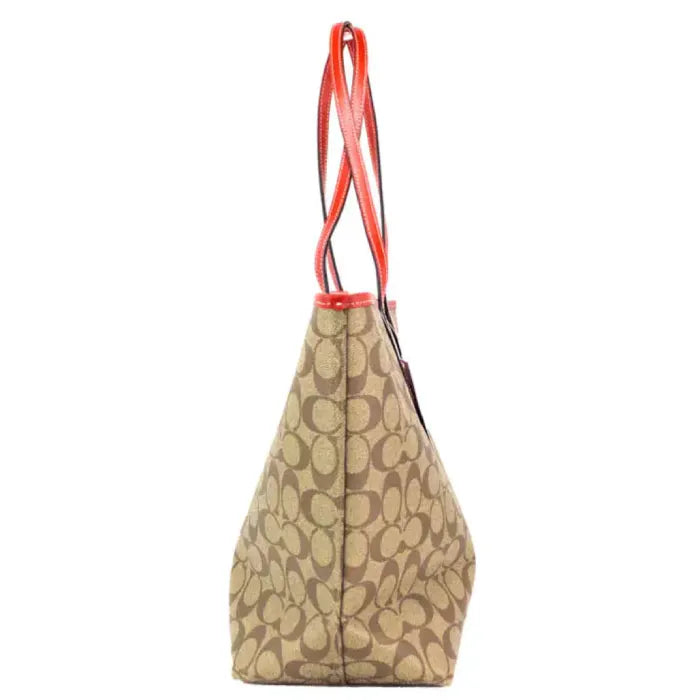 Side profile of Coach tote bag highlighting monogram pattern and red leather handles.