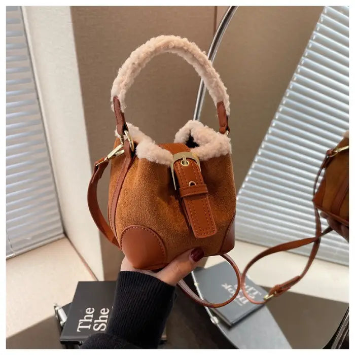 Close-up of cognac brown suede bucket bag featuring sherpa-trimmed handle and leather strap