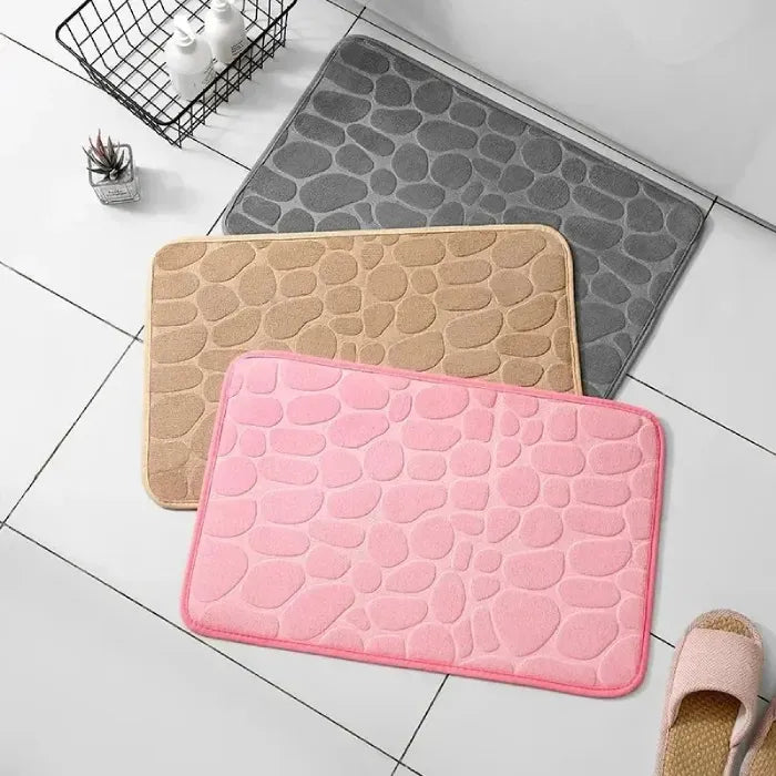 Assortment of colorful bath mats in pink, grey, and beige for modern homes.